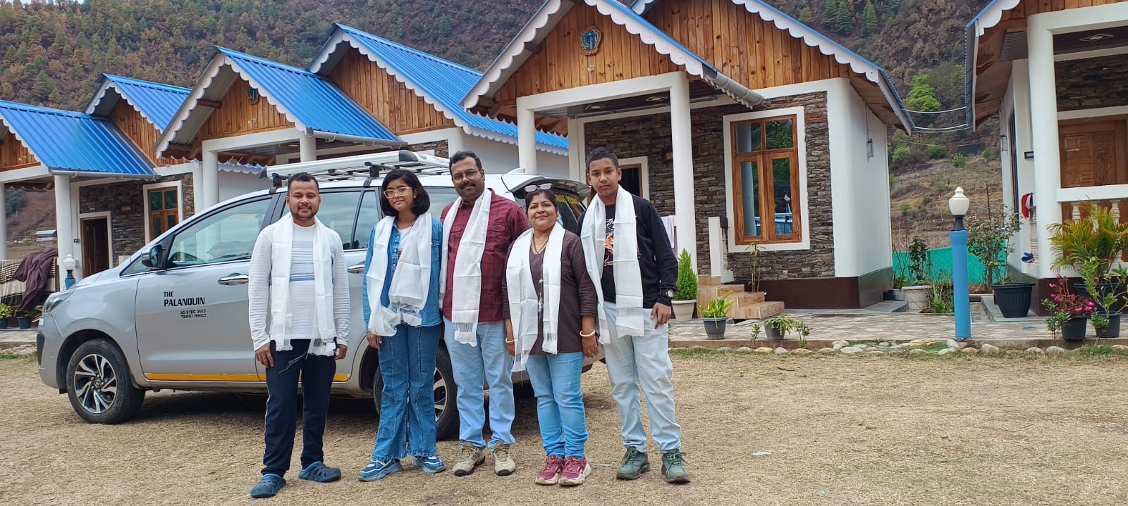 Guests with driver wearing traditional white scarves beside PalanQuin Innova